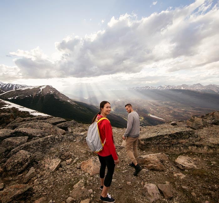 Two people walk in an alpine landscape on a rocky path.